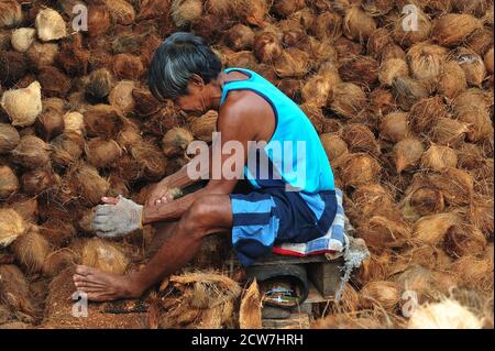 Bangkok, Thailand. September 2020. Ein Arbeiter schält Kokosnüsse in einem kleinen Werk in Bangkok, Thailand, 28. September 2020. Jeder der Arbeiter im Werk schält hier etwa 3,000 Kokosnüsse pro Tag, um den Bedarf des Marktes zu decken. Quelle: Rachen Sageamsak/Xinhua/Alamy Live News Stockfoto