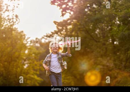 Kleiner Junge, der im Park mit dem Spielzeugflugzeug spielt Stockfoto