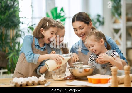 Glückliche liebevolle Familie bereiten gemeinsam Bäckerei. Mutter und Kinder Töchter Mädchen kochen Kekse und Spaß in der Küche. Hausgemachtes Foo Stockfoto