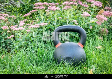 Eisen-Kettlebell auf dem grünen Rasen in einem Hinterhof - outdoor-Fitness-Konzept Stockfoto