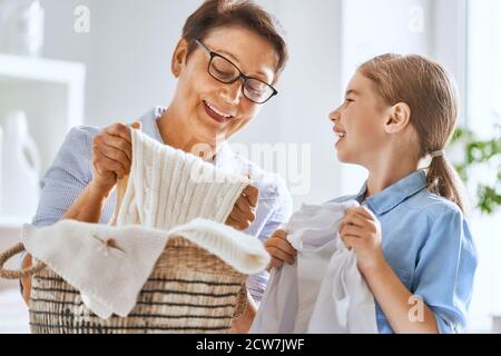 Schöne Frauen und Kind Mädchen kleinen Helfer haben Spaß und lächeln, während die Wäsche zu Hause. Stockfoto