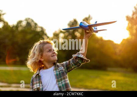 Kleiner Junge, der im Park mit dem Spielzeugflugzeug spielt Stockfoto