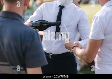 Kellner gießt Champagner-Gläser für Gäste auf Outdoor-Party Stockfoto
