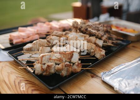 Zubereitung von Lachs, Chiken und Schweinefleisch auf Party im Freien Stockfoto