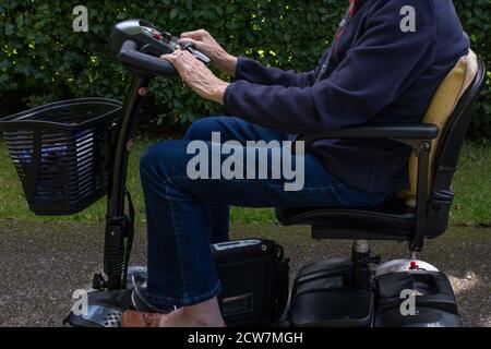 Eine alte Dame in einem blauen Pullover und Jeans, die einen Bewegungs-Roller reitet, nur mit den Schultern nach unten geschossen. Stockfoto