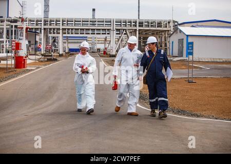 Ölraffinerie und Gasverarbeitungsanlage. Drei Spezialisten Ölingenieure auf Pipelines Hintergrund. Zhaik-Munai Öllagerstätte, Kasachstan. Stockfoto