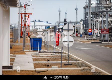 Ölraffinerie und Gasverarbeitungsanlage in der Wüste. Ingenieur in roten Overalls und weißem Helm. Zhaik-Munai Öllagerstätte, Kasachstan. Stockfoto