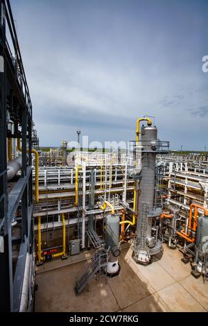 Grauer Destillationsturm (Raffiniersäule). Pipelines und Rohre Hintergrund. Ölraffinerie und Gasverarbeitungsanlage. Blauer Himmel. Stockfoto