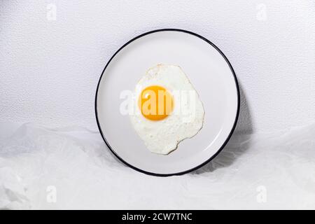 Spiegelei auf weißem Teller auf weißem Hintergrund. Trendiges Essen. Frühstück. Stockfoto