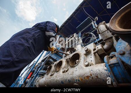 Zhaik-Munai Öllagerstätte, Kasachstan. Wartungsarbeiter, der den Motor der Schlammpumpe repariert. Baker Hughes Unternehmen. Stockfoto
