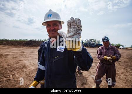 Zhaik-Munai Öllagerstätte, Kasachstan. Lächelnd und posiert glücklich Ölarbeiter Bohrinsel. Baker Hughes Unternehmen. Stockfoto