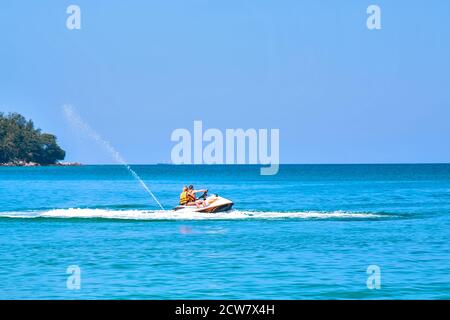 Сouple, Mann und Frau genießen es, Hydrocycle im blauen Ozean zu reiten. Insel im Hintergrund Stockfoto