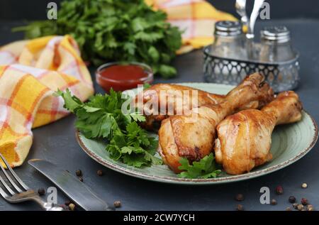 Hähnchendrumsticks, gebacken in Marinade aus Ketchup, Sojasauce und Balsamico-Essig auf einem Teller auf dunklem Hintergrund, horizontales Format Stockfoto