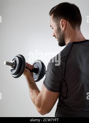 Muskulöser Mann mit Gewichten, isoliert auf grau Stockfoto