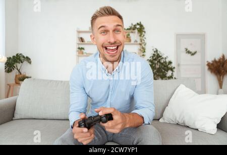 Junger Mann auf dem Sofa sitzend, der Videospiele spielt Stockfoto