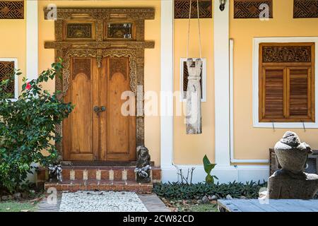 Eingang zum gelben Haus mit Fenster. Alte Holztür mit geschnitzten Mustern. Steinweg, der zu einer verschlossenen Tür führt. Stockfoto
