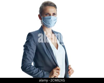 Geschäft während covid-19 Pandemie. Nachdenkliche elegante Geschäftsfrau mittleren Alters in einem grauen Anzug mit medizinischer Maske Blick in die Ferne gegen weiß Stockfoto
