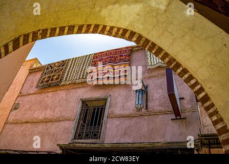 Teppiche zum Verkauf hängen an der typischen Gassenwand in der Medina von Marrakesch, Marokko. Stockfoto