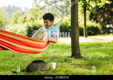 Junger Mann, der Casuals trägt, der auf einer Hängematte im Park ruht Stockfoto