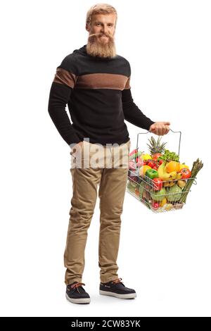 In voller Länge Porträt eines bärtigen Kerl trägt ein Einkaufen Korb mit Obst und Gemüse isoliert auf weißem Hintergrund Stockfoto