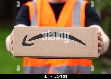 Ein Mann liefert eine Amazon-Box mit dem Amazon Lächeln Logo in Großbritannien Stockfoto