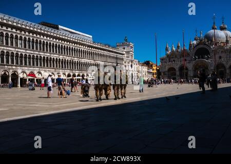 Rückansicht einiger Soldaten der italienischen Armee, die den Markusplatz in Venedig überquerten. Sie gehen in Richtung der Nordseite des Platzes, AMO Stockfoto