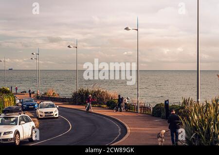 Alltag. Strandpromenade. Wandern und Übungen. Menschen, die am Meer entlang laufen Graystones. Irland. Stockfoto