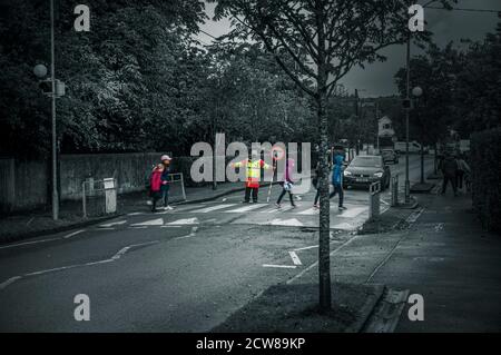 Alltag. Schullauf: Kinder überqueren die Straße mit Hilfe von Crosswalk Begleiter. Greystones. Irland. Stockfoto