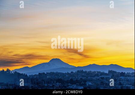 Luftbild von Quito bei Sonnenaufgang mit der Cayambe Vulkan Silhouette, Anden Berge, Ecuador. Stockfoto