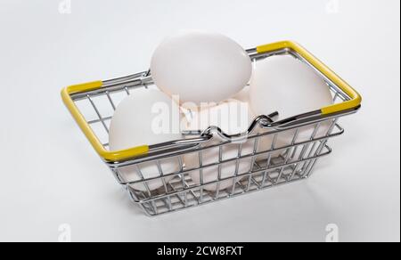 Frische Eier in einem Warenkorb. Der Korb ist vollständig voll. High-Angle-Aufnahme. Korb mit den Händen nach unten. Shopping, Einkauf und Food Delivery Konzept. Weiß Stockfoto