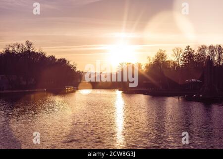 Letzten Herbst Sonnenuntergang über dem See im Stadtpark. Der Weg von der Sonne auf dem Wasser, Lichtreflexe Stockfoto