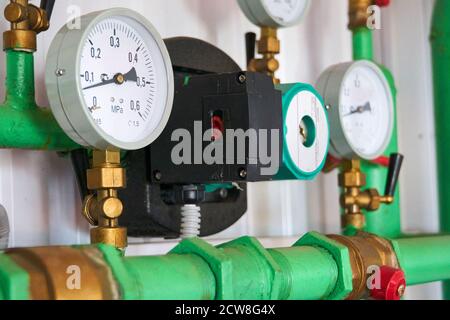 Drucksensoren an der in grünes Heißwasser lackierten Pipeline zeigen den Druck an. Stockfoto