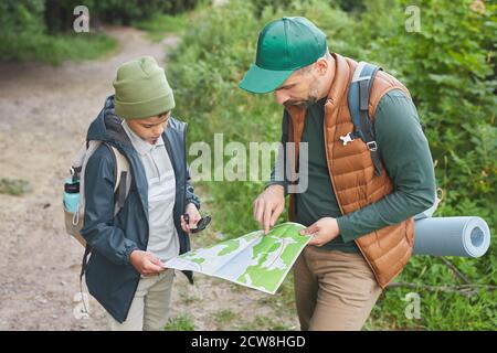 Porträt von Vater und Sohn zusammen wandern und betrachten Karte beim Erkunden von Pfaden im Wald Stockfoto