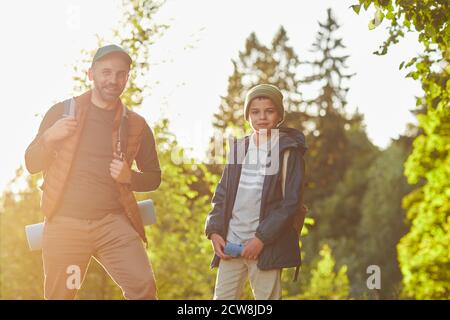 Porträt von reifen Vater und Sohn Wandern im Freien in Sonnenlicht und Blick auf Kamera, kopieren Raum Stockfoto