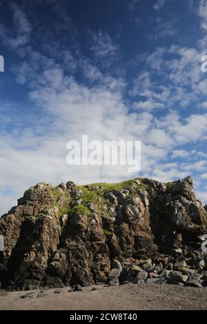 Dunure, Ayrshire, Schottland, UK.EIN Felsvorsprung mit Gras bedeckt mit blauem Himmel und weißen Wolken Stockfoto