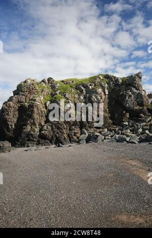 Dunure, Ayrshire, Schottland, UK.EIN Felsvorsprung mit Gras bedeckt mit blauem Himmel und weißen Wolken Stockfoto