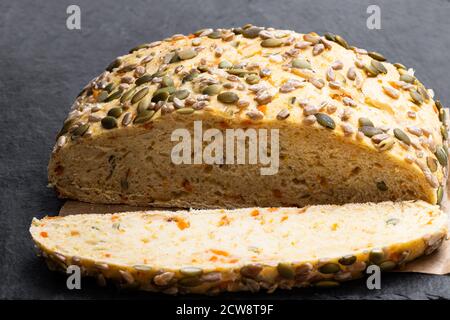 Saatgut fallenden Karotte Brot bloomer Laib auf schwarzen Stein Hintergrund Stockfoto