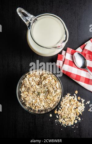 Müsli, Cerealien. Gesundes Frühstück mit Haferflocken und Milch auf schwarzem Tisch. Draufsicht. Stockfoto