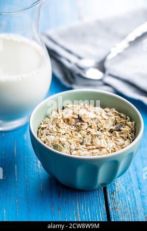 Müsli, Cerealien. Gesundes Frühstück mit Haferflocken in Schale auf blauem Holztisch. Stockfoto