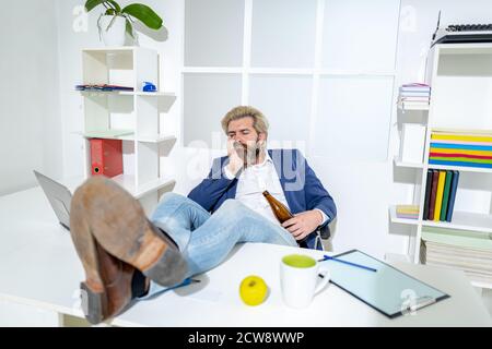 Junger Geschäftsmann Mitarbeiter trinkt im Büro am Schreibtisch. Traurig gestresst alkoholischen Missbrauch Kerl betrunken fühlen einsam verzweifelt über sucht. Stockfoto