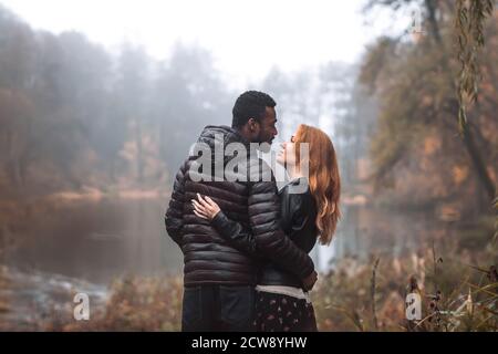 Interracial paar posiert im Herbst Blätter Hintergrund, schwarzer Mann und weiß rothaarige Frau Stockfoto