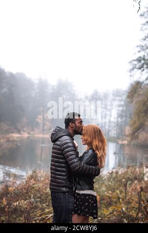 Interracial paar posiert im Herbst Blätter Hintergrund, schwarzer Mann und weiß rothaarige Frau Stockfoto