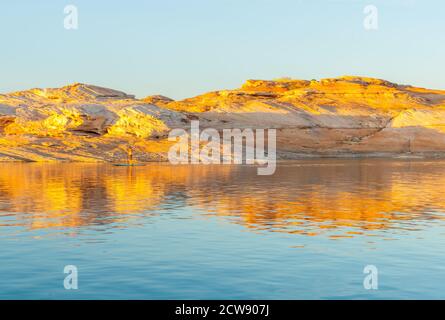 Als Sonnenuntergänge Licht trifft die Felsen Böschungen mit einem goldenen Glow auf der anderen Seite Lake Powell ein künstlich anmuttes Reservoir Der Colorado River in Utah und Arizona Stockfoto