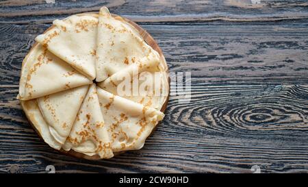 Blick von oben auf einfache hausgemachte Pfannkuchen auf dem dunklen Holztisch. Goldenes einfaches Dreieck Crepe für ein Frühstück. Stockfoto