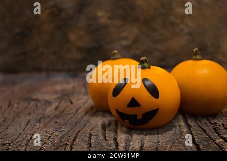 Halloween-Karte. Drei orangefarbene Kürbisse. Einer von ihnen ist Jack. Sie liegen in einem Korb auf der Rinde eines Baumes Stockfoto