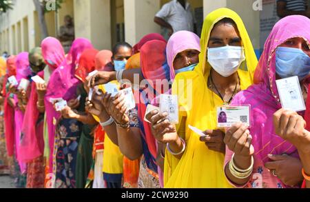 Beawar, Rajasthan, Indien, 28. September 2020: Verschleierte Frauen aus Rajasthani warten in langen Schlangen, um während der Panchayati Raj-Wahlen in einem Wahllokal Stimmen abzugeben, inmitten der laufenden Coronavirus-Pandemie im Dorf Jhala KI Chauki in der Nähe von Beawar. Über 83.50 Prozent der 31.95-lakh Wähler ihre Stimmen in der ersten Phase der 947 Gramm Panchayat (Dorfrat) Wahlen in 25 Bezirken im ganzen Staat. Die Richtlinien im Zusammenhang mit COVID-19 wurden bei der Wahl nicht befolgt. Die Wähler tragen Gesichtsmasken, haben aber keine soziale Distanzierung beibehalten. Kredit: Sumit Saraswat/Alamy Live Nachrichten Stockfoto