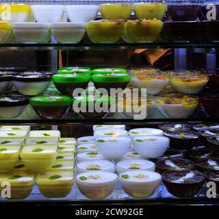 Fruchtige und Schokoladenmilchdesserts sehen in der Glasvitrine im Dessertladen wunderschön aus. Stockfoto