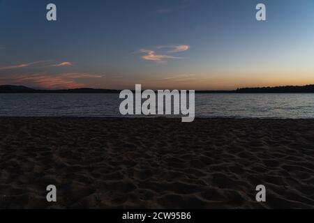 Der Sonnenuntergang über einem See von einem Strand in Lake Placid, NY Stockfoto