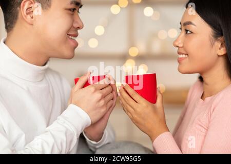 Liebevolle Asiatische Paar Trinken Kaffee Holding Tassen Sitzen Zu Hause Stockfoto