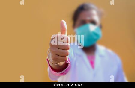 Arzthände mit Daumen nach oben, Ärztin trägt eine schützende Gesichtsmaske Stockfoto